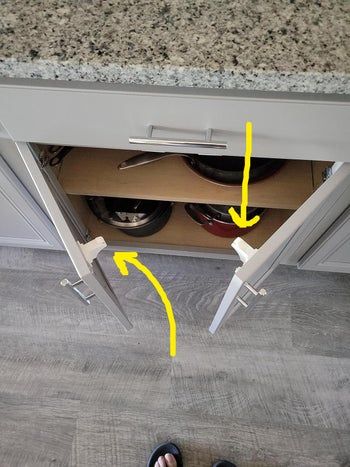 a kitchen cabinet filled with pots and pans, photographed from a top-down angle