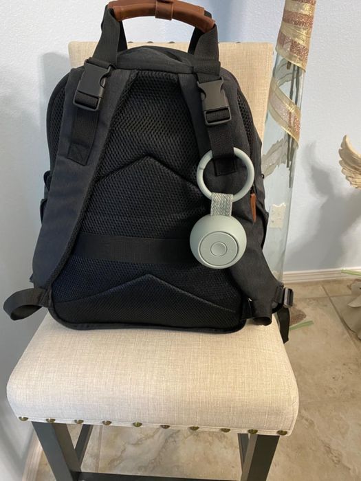 A black backpack with a green portable sound machine clipped to it