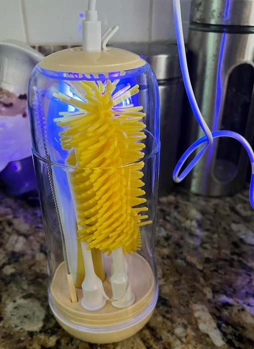 An electric bottle brush featuring yellow bristles and an internal UV light