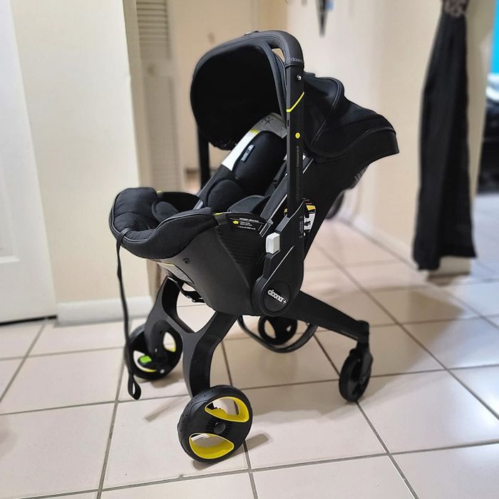 A sleek black Doona infant car seat stroller shown in its unfolded form