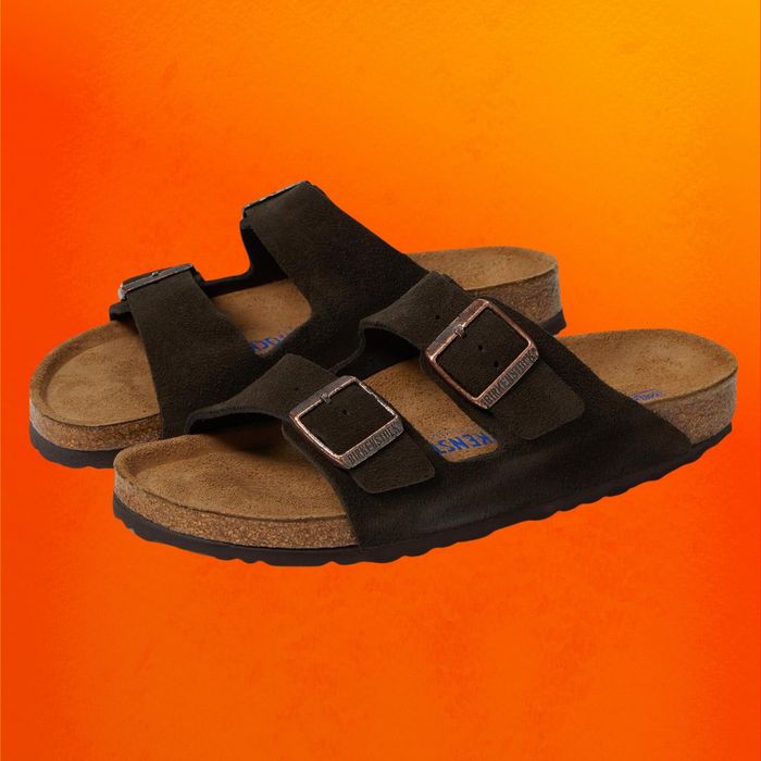 Black Birkenstock slide sandals showcased on an orange background