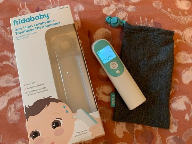 A 3-in-1 thermometer by Fridababy, complete with packaging, a carrying pouch, and a visible temperature reading
