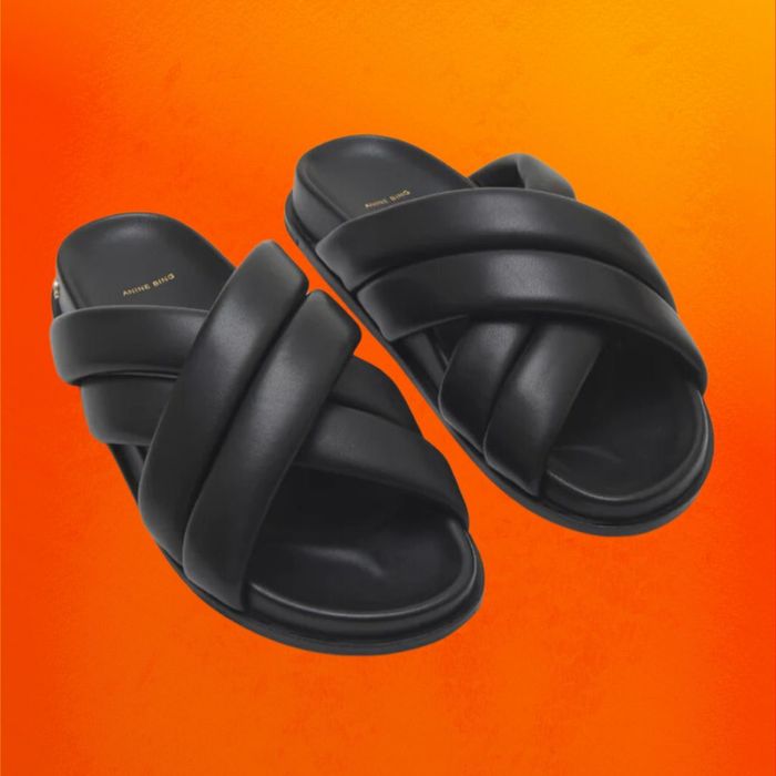 Black slide sandals displayed on an orange background