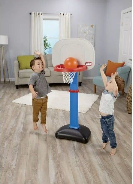 Two boys having fun playing basketball indoors.