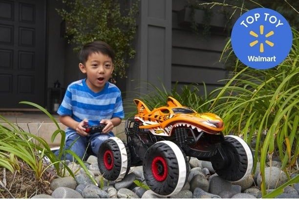 A young boy enjoys playing with his Hot Wheels monster truck outside.
