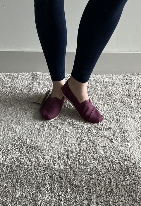 A reviewer wearing bright red Toms loafers