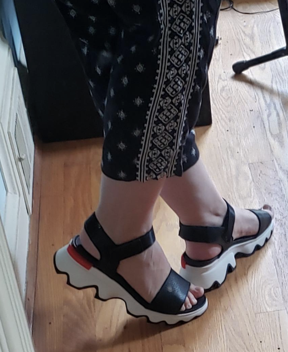 Reviewer photo showing a close-up of black strappy sandals with white soles.