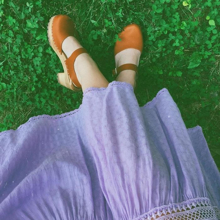 A reviewer showcasing the tan clogs