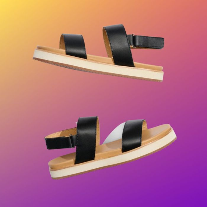 Black wide-strap sandals set against a gradient purple and yellow background
