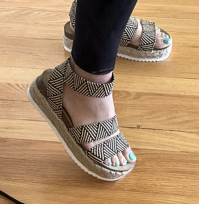 A reviewer wearing shoes with a geometric print design