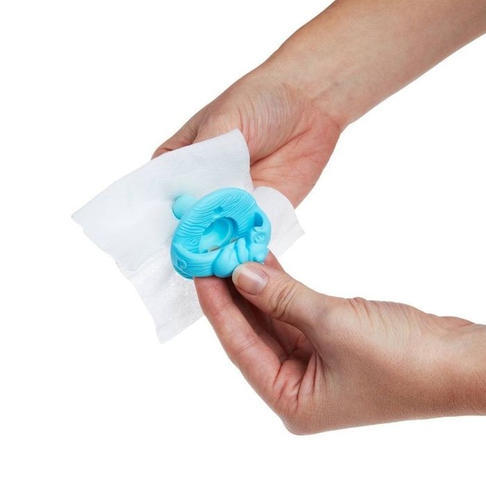 A pacifier being cleaned with a wipe