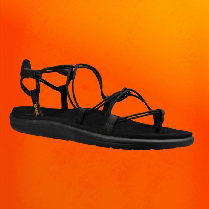 Black strappy Teva sandals set against an orange backdrop
