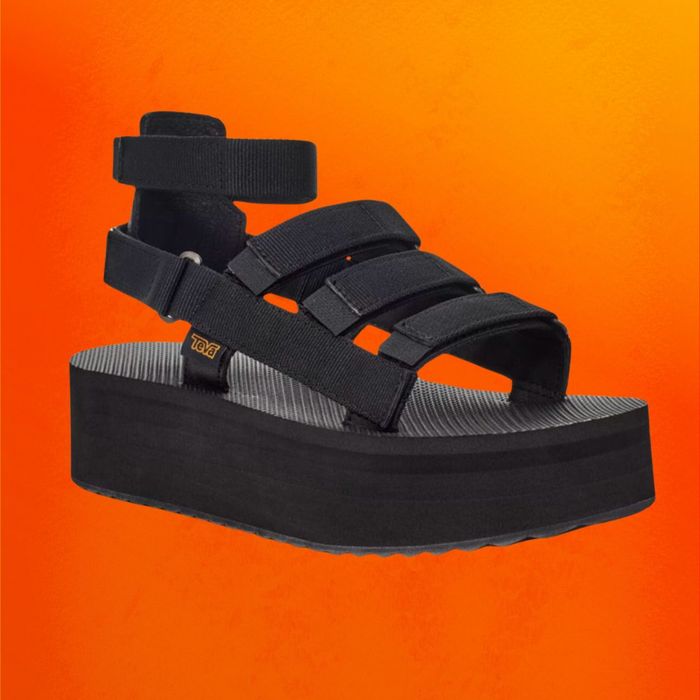 Black platform Teva sandals showcased on an orange background.