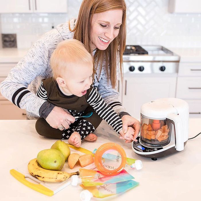 A parent and child preparing homemade baby food using a Baby Brezza baby food maker