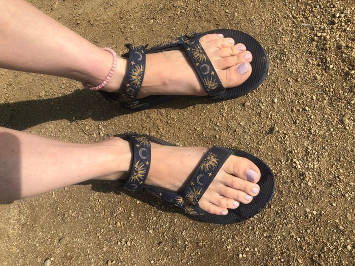 The reviewer is wearing black Teva sandals with sun and moon designs on the straps.
