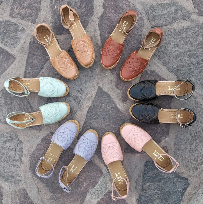 A vibrant assortment of huarache sandals in various colors, arranged neatly in a circle, highlighting their diversity and style.