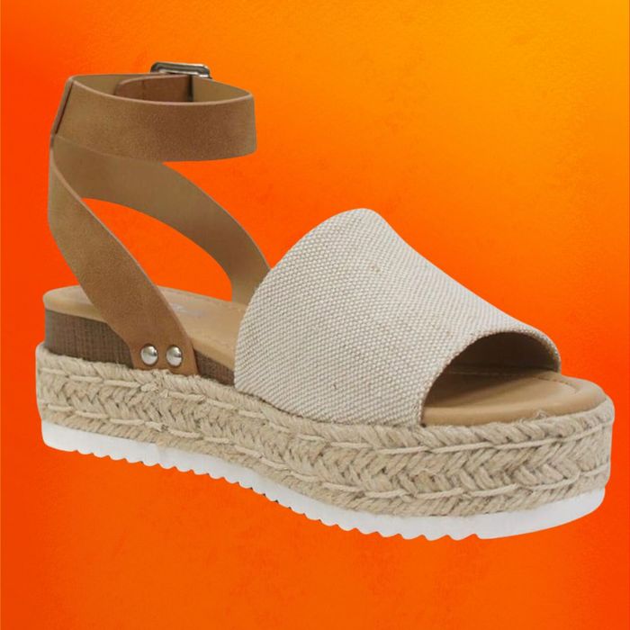 Neutral-toned espadrille sandals displayed on an orange background