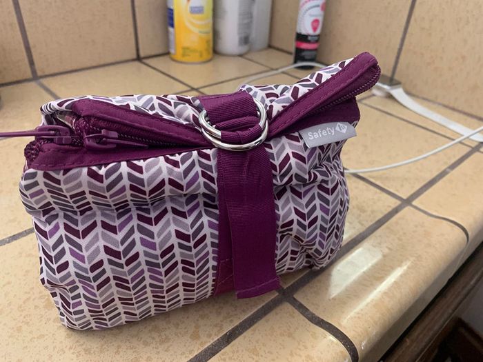A stylish toiletry bag featuring a patterned design and a circular metal ring