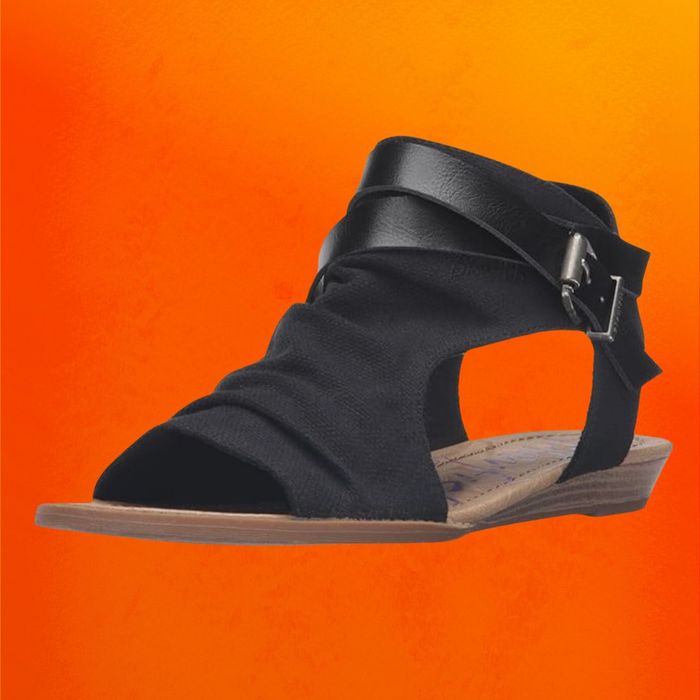 Black suede wedge sandals showcased on an orange background