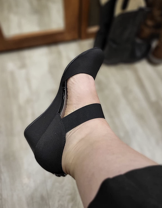 Reviewer demonstrating the wedge pumps featuring an elastic strap for added comfort.