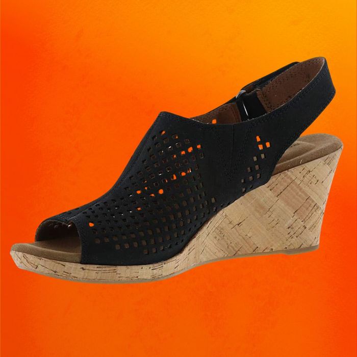 Black wedge sandals featuring a cork sole, set against an orange backdrop