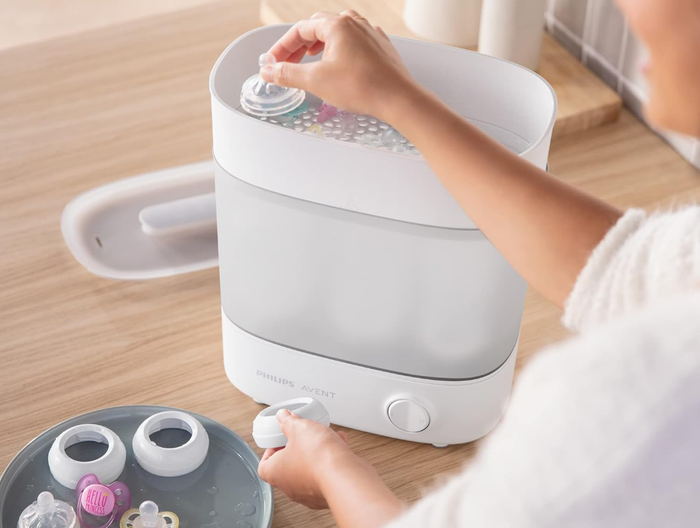 A parent loading pacifiers and bottle parts into the Philips Avent sterilizer for quick and efficient cleaning