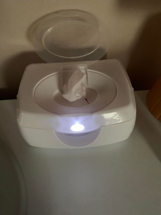 A wipe warmer with its lid open, revealing a warm wipe ready for use