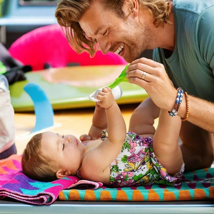 A model holding a baby with a bag dispenser nearby