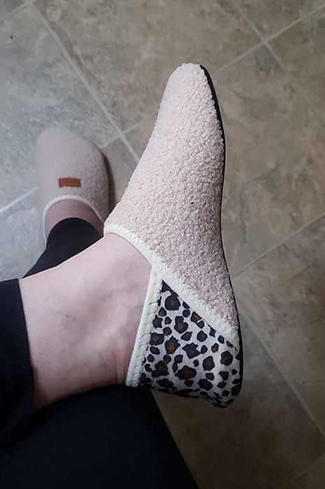 A reviewer with one foot crossed over the other, wearing yellow and cheetah print slippers