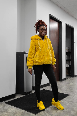 Image of a reviewer dressed in black leggings, a vibrant yellow fluffy jacket, and sneakers in a matching yellow hue