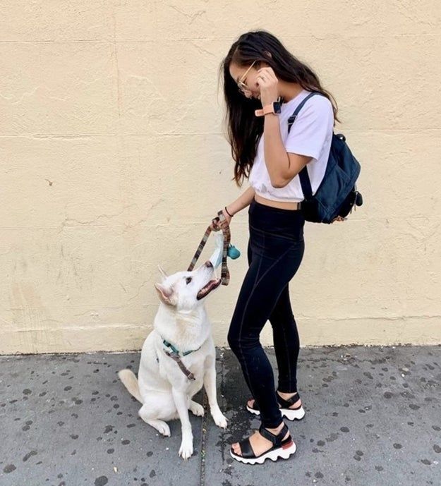 Reviewer photo of a person standing with their dog while wearing black and white sandals.