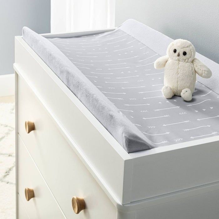 A baby changing table featuring a cozy, patterned mat and an adorable stuffed owl on top