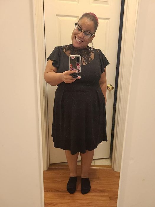 Reviewer showcasing a black cocktail dress with a lace neckline