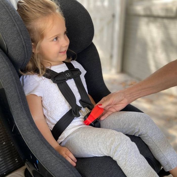 An adult using a buckle release tool on a car seat