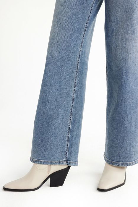 Person wearing blue jeans paired with white and black heeled boots.