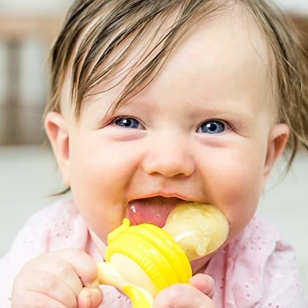 A baby happily chewing on a silicone food feeder pacifier