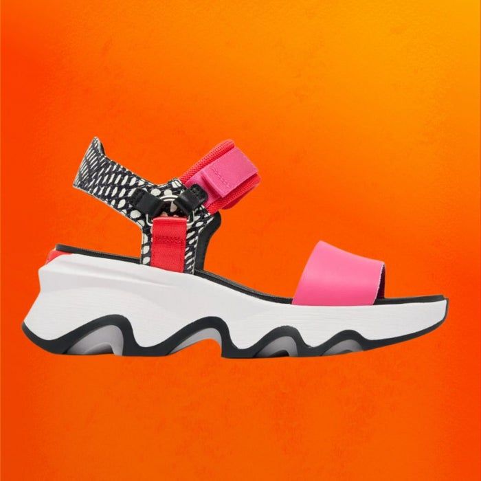 The Sorel Kinetic Impact Y-Strap sandals showcased on an orange backdrop