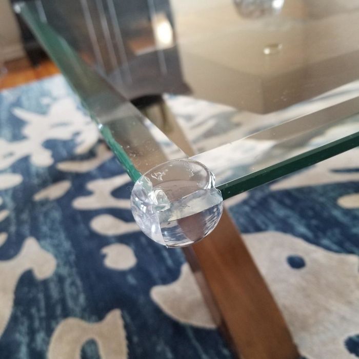 A clear corner guard installed on the edge of a glass table, as shown in a reviewer's photo