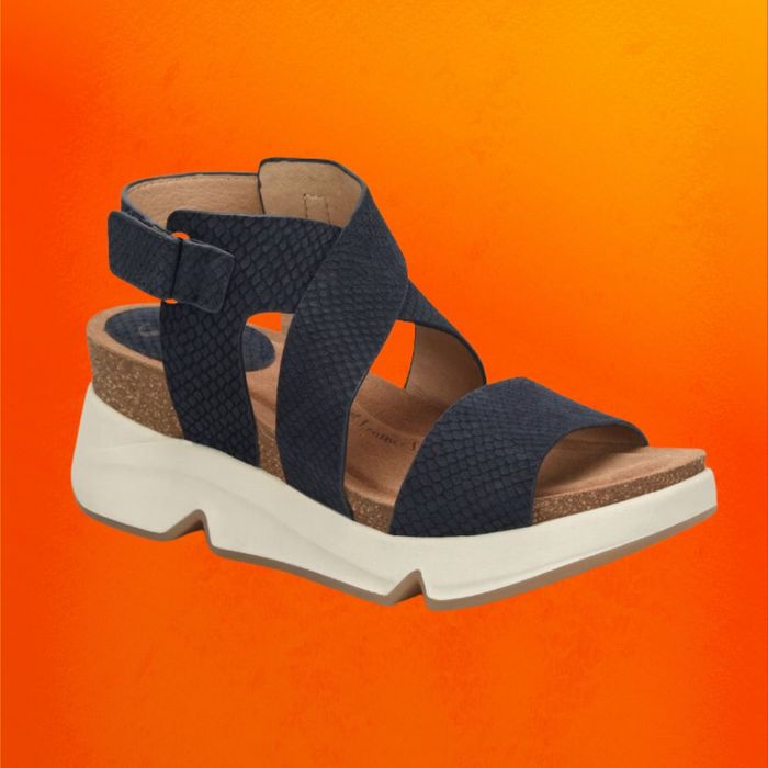 Navy wedge sandals with crisscross wide straps, set against an orange backdrop