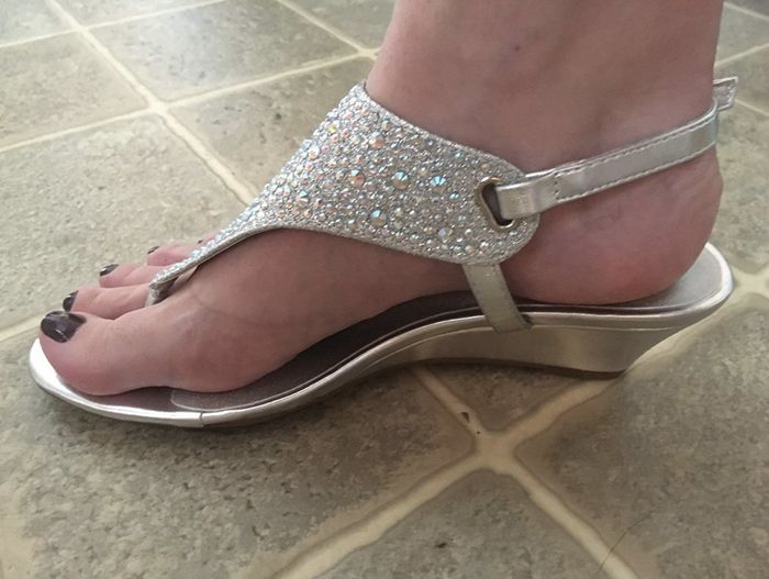 The same reviewer displaying the side view of a low wedge sandal with an ankle strap