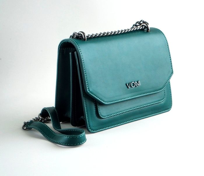 The handbag features a sleek rectangular shape with a silver chain strap, a soft center section, a front flap, two interior compartments, and a front-slip pocket for easy organization.