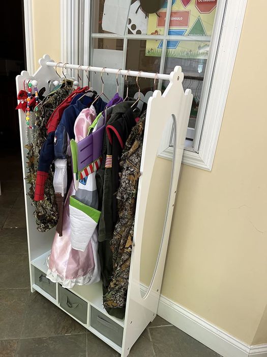 A costume rack filled with a variety of children’s outfits, including a fairy princess gown and a camouflage ensemble, ready for playtime adventures.