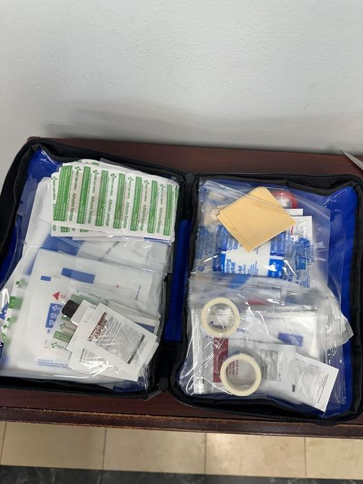 An open first-aid kit displaying various medical items like bandages, antiseptic wipes, medical tape, and gauze pads