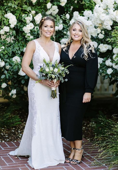 a reviewer in a black dress standing beside a bride