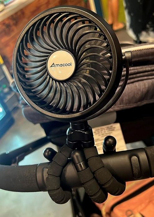 An Amacool portable fan clipped to a stroller handle, shown in a retail environment