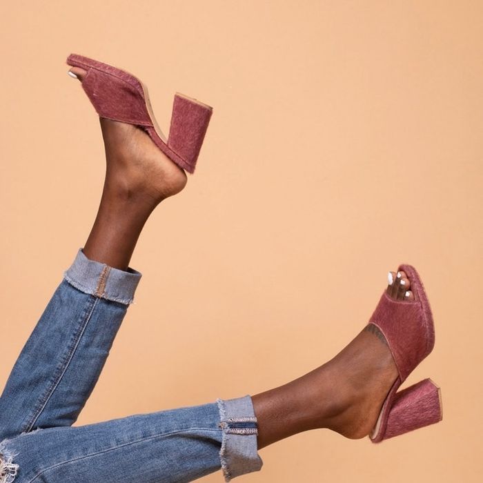 The model is seen in pink heeled mules that have a unique texture.
