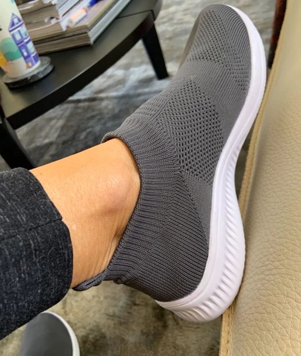 A reviewer is pictured wearing the gray slip-ons