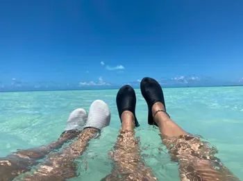 Two people wearing the shoes while standing in the ocean