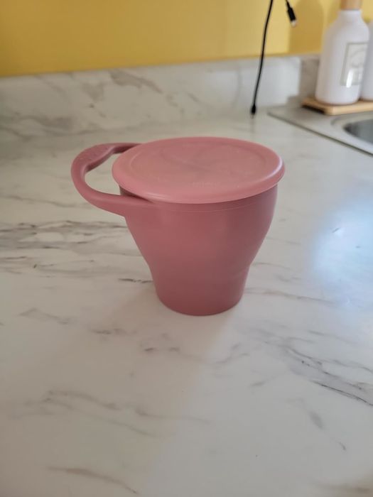 A foldable silicone cup with a lid, displayed on a kitchen counter, showcasing its eco-friendly and compact design