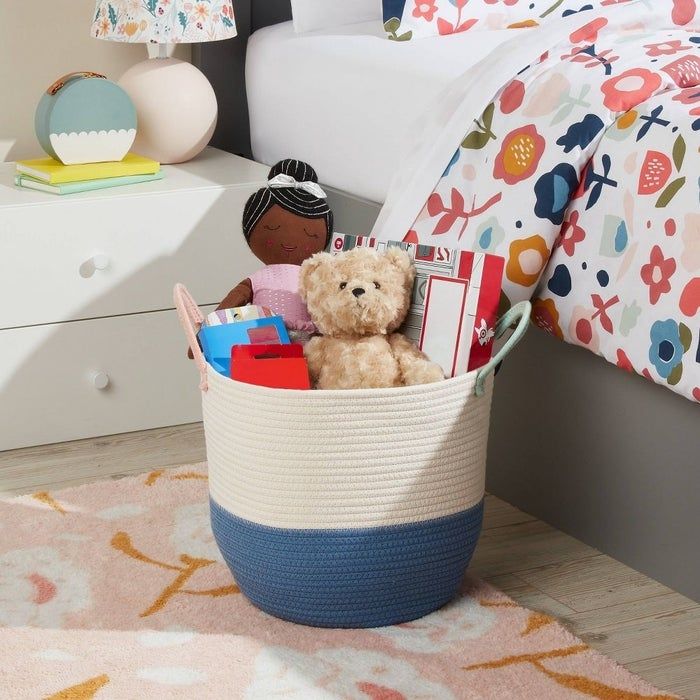 A woven basket containing toys and books, offering a stylish organizational option for a child's room.